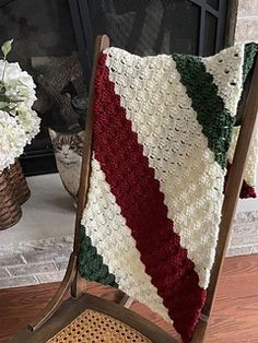 a crocheted blanket sitting on top of a wooden chair next to a fire place