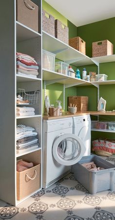 a washer and dryer in a small room with shelves on the wall behind them