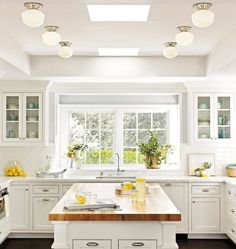 a large kitchen with white cabinets and wooden counter tops, an island in the middle