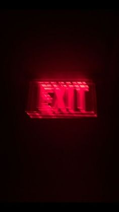 an exit sign lit up in the dark with red light at the top and bottom