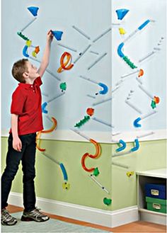 a young boy standing in front of a wall with magnets attached to the walls