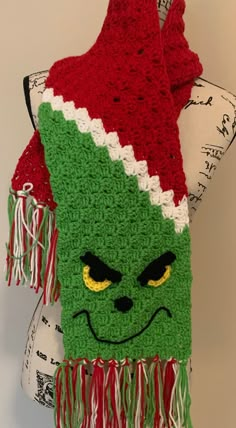 a crocheted scarf with an ugly grin face on it's side and fringes around the edges