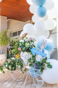 a bicycle decorated with flowers and balloons in front of a building