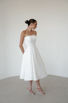 Elevate your wedding day look with our exquisite satin minimalist wedding dress. This sophisticated dress features a graceful midi length, perfect for the modern bride seeking timeless elegance. Discreet side pockets add a practical and stylish touch. A romantic lace-up back detail offers a customizable fit and a hint of classic charm. Crafted from luxurious satin, this dress combines simplicity with refined beauty, making it an ideal choice for your special day. Minimalistic Wedding Dress, Wedding Dress Midi, White Dress For Women, Midi Dress Satin, Wedding Midi Dress, Wedding Dress Tea Length, Dress Tea Length, Courthouse Wedding Dress, Minimalistic Wedding