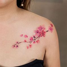 a woman wearing a black dress with pink flowers on her chest and shoulder tattoo design