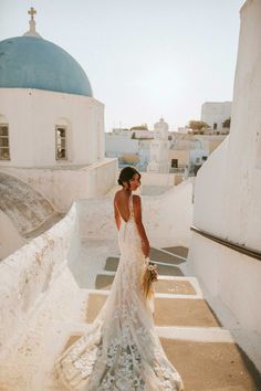 a woman in a wedding dress is standing on some steps with her back to the camera