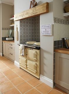 an old fashioned stove in the middle of a kitchen with tile flooring and walls