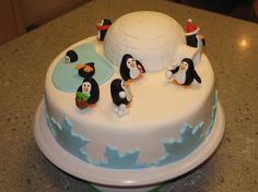 a birthday cake with penguins and an igloose on it's side