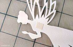 paper cut out of the shape of a woman's head on a tile floor