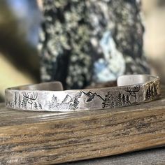 A rustic handmade bracelet that celebrates the beauty of nature and the majesty of the forest with the mountains, trees and deer hand stamped around the rustic silver cuff.   Perfect for the hunter or hiker in your life.  This engraved silver bracelet is hand forged and finished with a hammered finish to give it a rustic look, perfect for men and women alike.  Each bracelet is handmade, and no two will be exactly alike. Also please be aware that colors may vary due to viewing screens. If you hav Western Sterling Silver Cuff Bracelet Gift, Rustic Adjustable Stamped Cuff Bracelet, Adjustable Etched Sterling Silver Southwestern Bracelet, Silver Engraved Western Cuff Bracelet, Western Style Sterling Silver Bracelet Gift, Stamped 925, Deer Bracelet, Silver Engraved Bracelet, Black Sharpie, Copper Bracelet