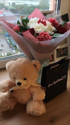 a teddy bear sitting next to a bouquet of flowers