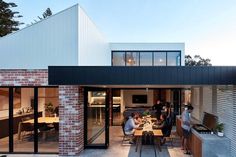 people are sitting at a table outside in front of a brick building with glass doors