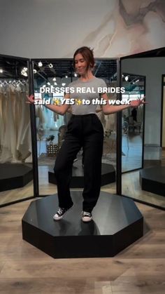 a woman standing on top of a black platform in front of a display case with clothes