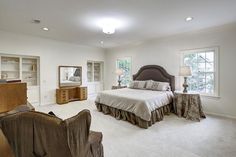 a large bedroom with a bed, chair and desk in it's center area