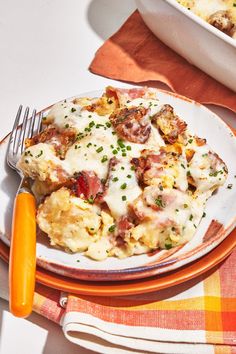 an orange and white plate topped with food next to a bowl of macaroni and cheese