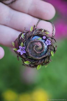 a hand holding a small bird's nest with purple flowers on the outside and inside