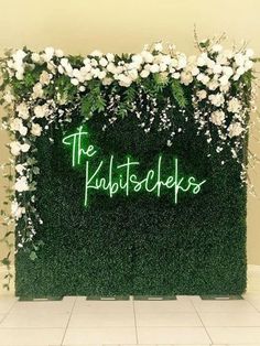 a green wall with white flowers and the words the knottscheps on it