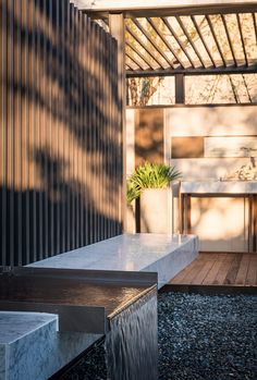 an outdoor shower with water running from it's sides and a bench in the background