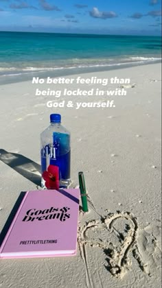 a notepad, pen and bottle on the beach with a message written in the sand