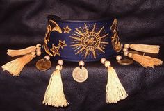 a blue belt with gold tassels and medallions on the front, sitting on a black leather surface