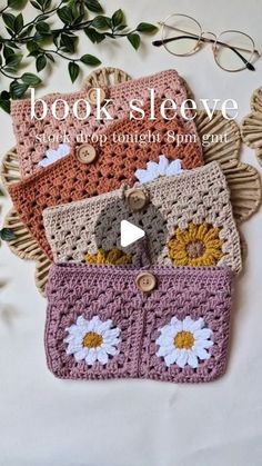 three crocheted purses sitting on top of a table next to green leaves