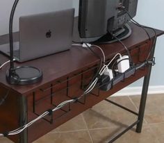 a laptop computer sitting on top of a wooden desk with wires attached to the keyboard