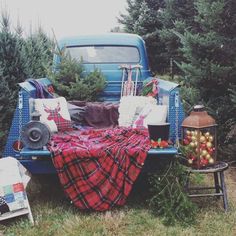 an old blue truck with christmas trees in the back and blankets on it's bed