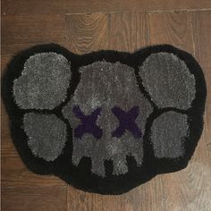 a black and gray rug with two purple crosses on the middle is laying on a wooden floor