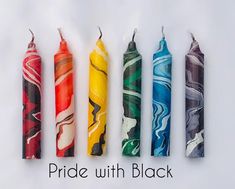 four different colored candles with the words pride with black written below them in white text