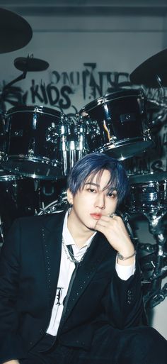 a man with blue hair sitting in front of a drum set and posing for the camera