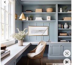 a room with blue walls and shelves filled with books, vases and flowers on the desk