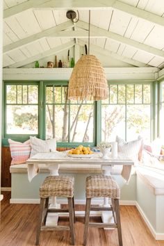 a table with two stools in front of it and a basket hanging from the ceiling