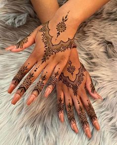 two hands with henna tattoos on them