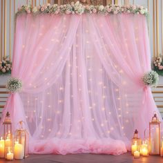 a pink wedding stage set up with candles and flowers on the side, surrounded by sheer curtains