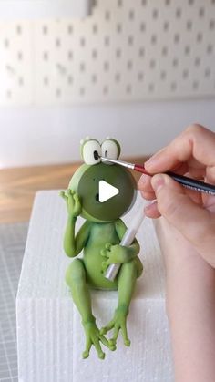 a person holding a pen and drawing a frog