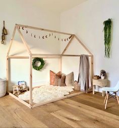 a wooden house bed sitting on top of a hard wood floor next to a white wall