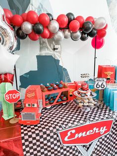 an assortment of desserts and balloons are displayed on a checkered tablecloth in front of a backdrop