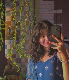 a woman taking a selfie with her cell phone in front of some green plants