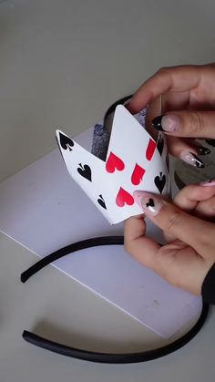 two hands are making a paper boat that looks like a king and queen with hearts on it