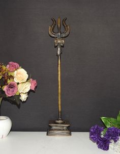 a vase filled with flowers next to a decorative metal candle holder on a white table