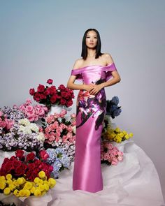 a woman in a pink dress standing next to flowers