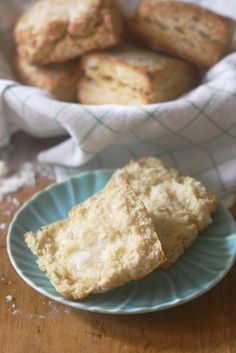 some scones are on a blue plate next to a bowl of biscuits and a napkin