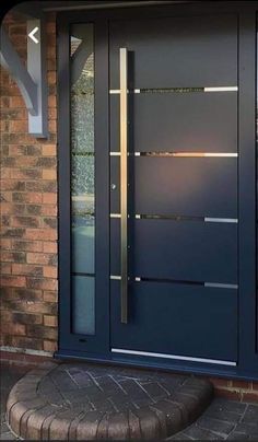 a blue front door with glass panels and a sidelight on the brick wall behind it