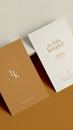 two business cards sitting on top of each other with the letter k in gold foil