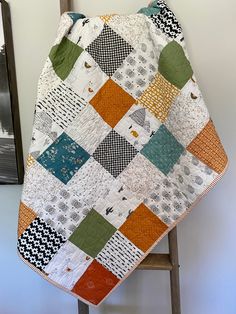 a quilted blanket sitting on top of a wooden chair next to a framed photo