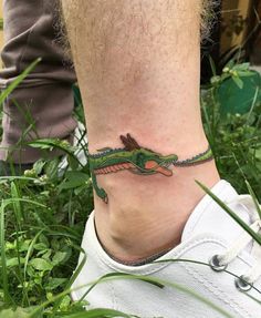 a foot with a tattoo on it that has a green alligator on it's side