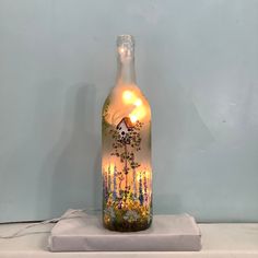 a glass bottle with a painting on it sitting on top of a white table cloth