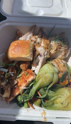 a white takeout container filled with food including meat and veggies, bread