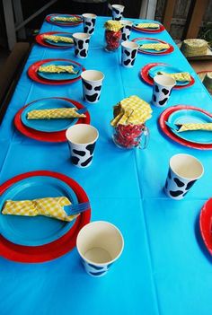 a blue table with red and white plates, cups and napkins on top of it