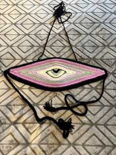 a purse with an eye on it sitting on the floor next to a string and thread